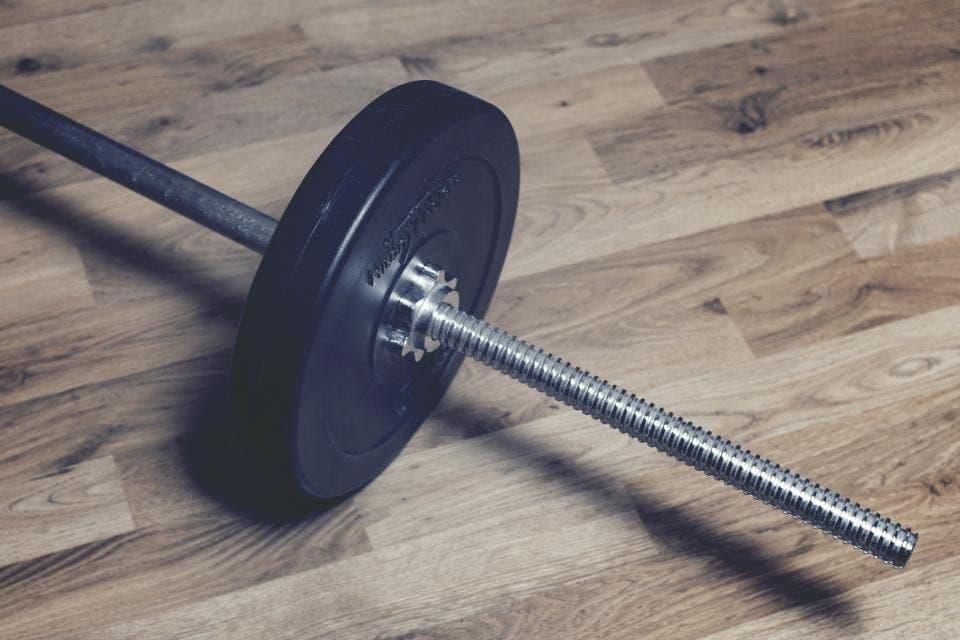 Loaded barbell resting on a wooden floor